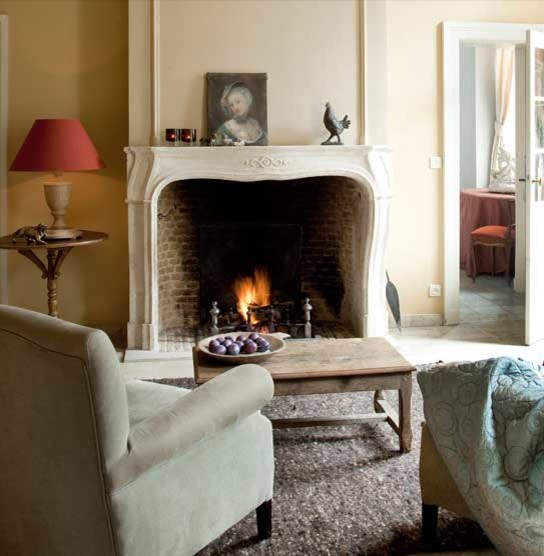 Immagine di un piccolo soggiorno mediterraneo aperto con sala formale, pareti beige, camino classico, cornice del camino in pietra e nessuna TV