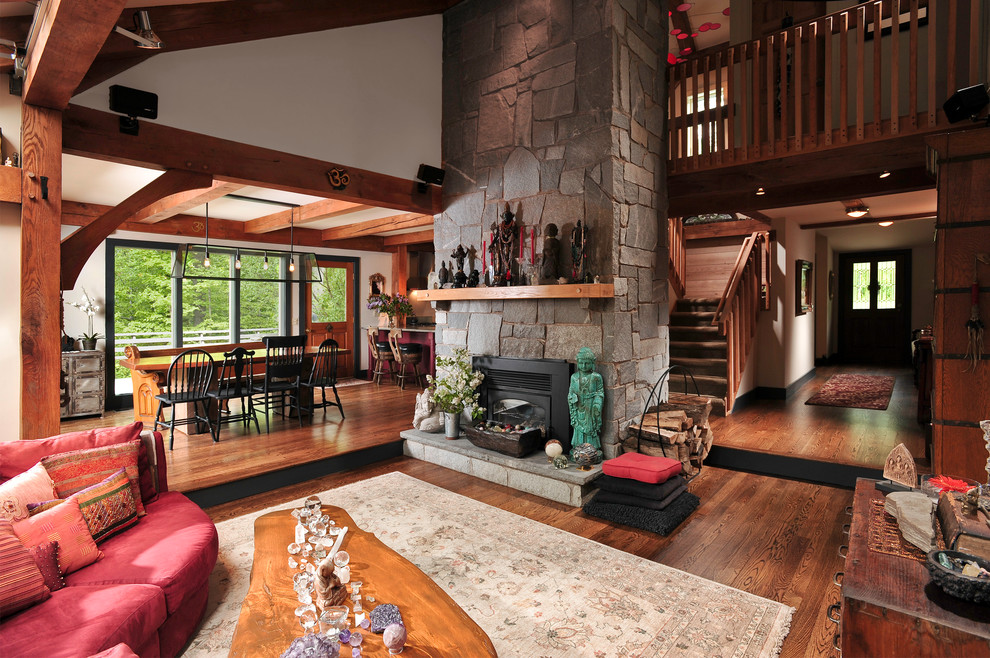 Large rustic open plan living room in Chicago with a stone fireplace surround, beige walls, dark hardwood flooring, a standard fireplace and brown floors.