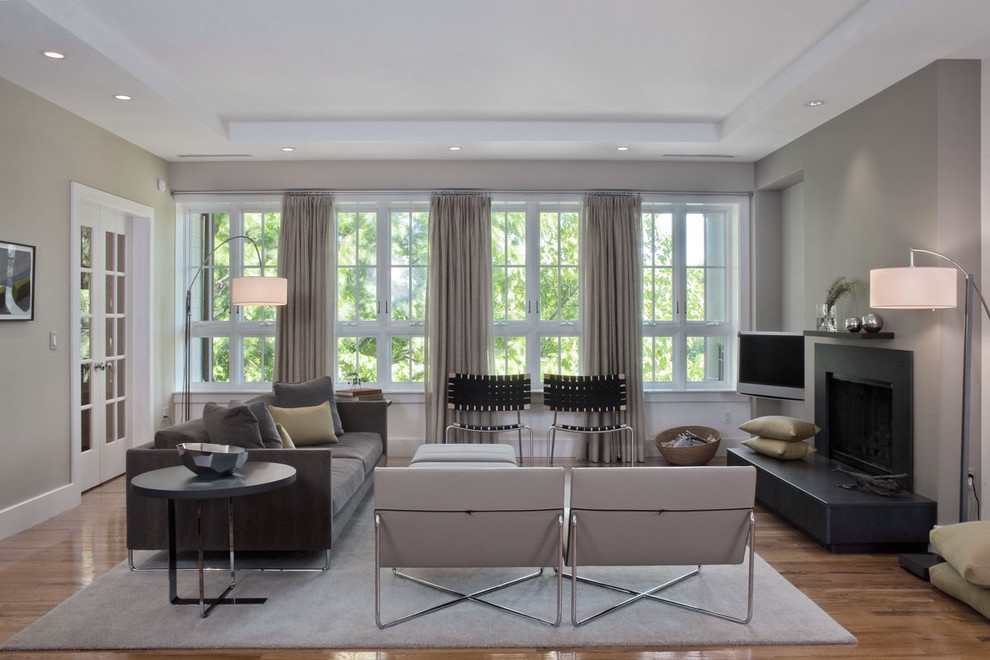 Пример оригинального дизайна: гостиная комната в современном стиле с серыми стенами и стандартным камином