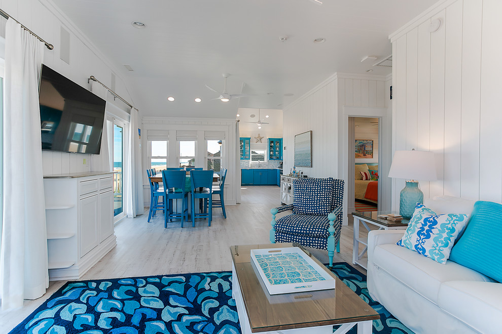 Inspiration for a mid-sized coastal open concept vinyl floor living room remodel in Other with white walls and a wall-mounted tv