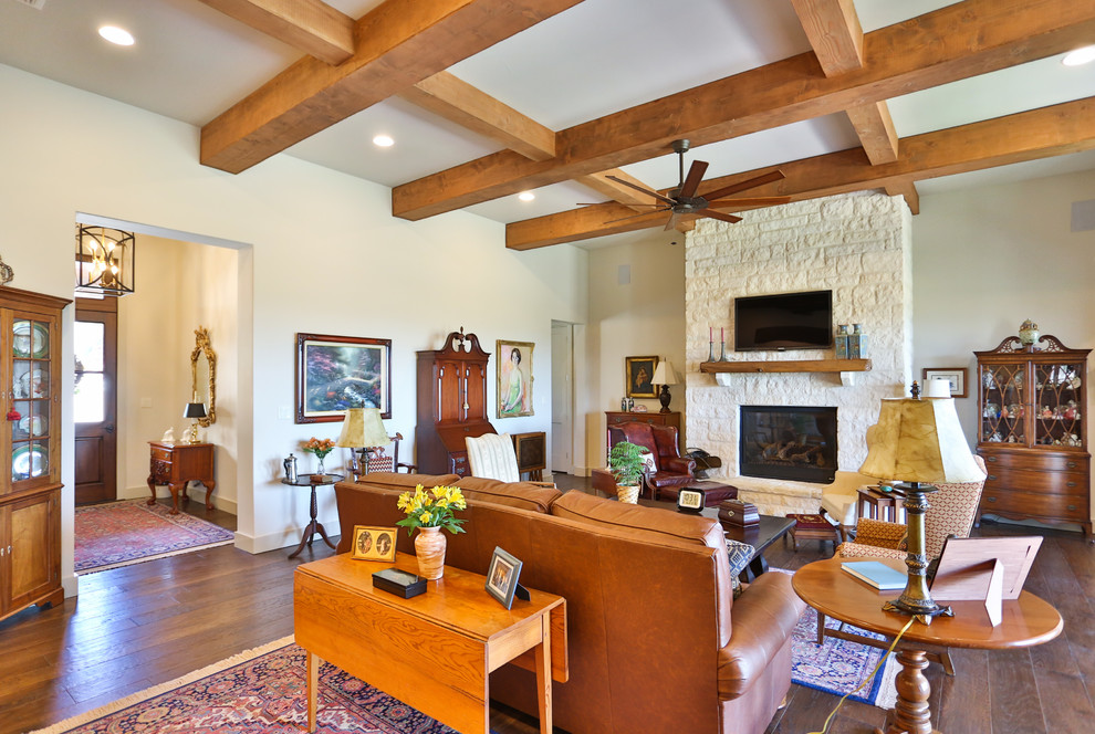 Photo of a medium sized traditional formal open plan living room in Austin with white walls, medium hardwood flooring, a standard fireplace, a stone fireplace surround, a wall mounted tv and brown floors.