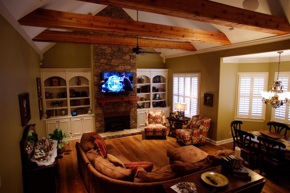 Foto de salón abierto rural de tamaño medio con suelo de madera en tonos medios, suelo marrón, todas las chimeneas, marco de chimenea de piedra y televisor colgado en la pared