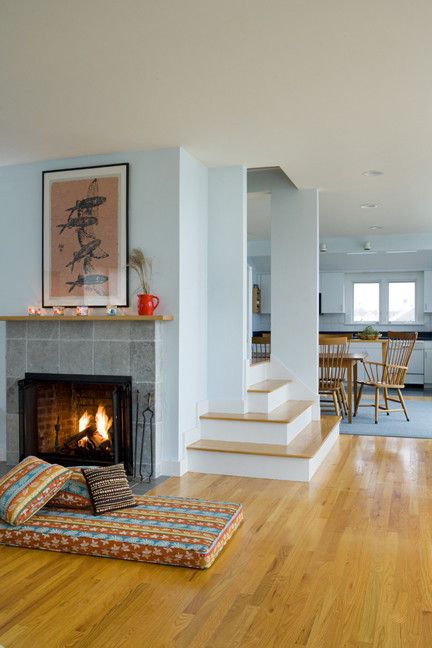 Modelo de salón abierto minimalista con paredes azules, suelo de madera clara, todas las chimeneas y marco de chimenea de piedra