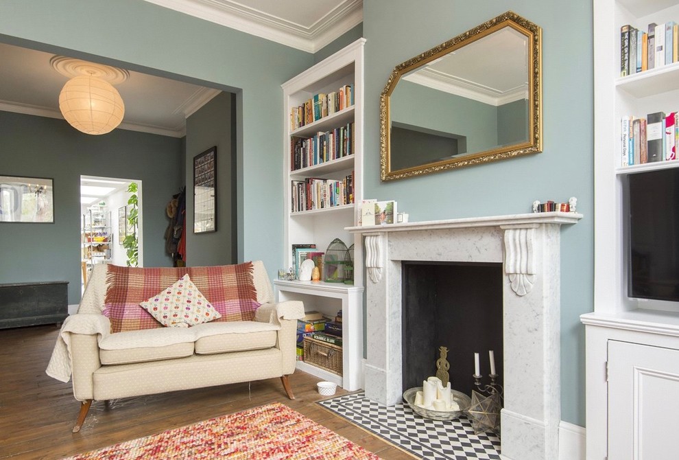 Ispirazione per un soggiorno vittoriano con pareti blu, pavimento in legno massello medio, camino classico e pavimento marrone