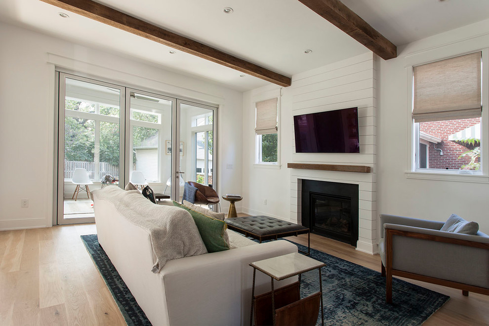 Cette image montre un grand salon rustique ouvert avec un mur blanc, parquet clair, une cheminée standard, un manteau de cheminée en bois et un téléviseur fixé au mur.
