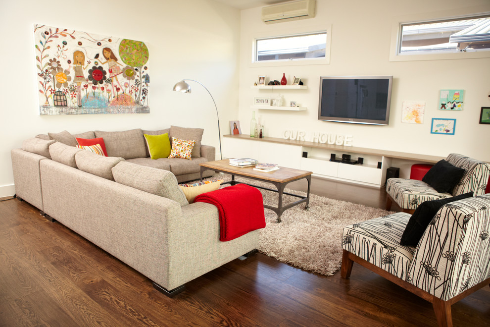 Cette image montre un grand salon design ouvert avec un mur blanc et un téléviseur fixé au mur.