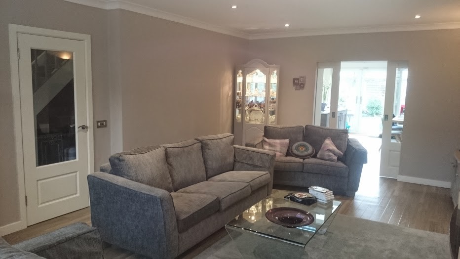 This is an example of a large modern enclosed living room in Dublin with a music area, grey walls, medium hardwood flooring, a wood burning stove, a plastered fireplace surround and a wall mounted tv.