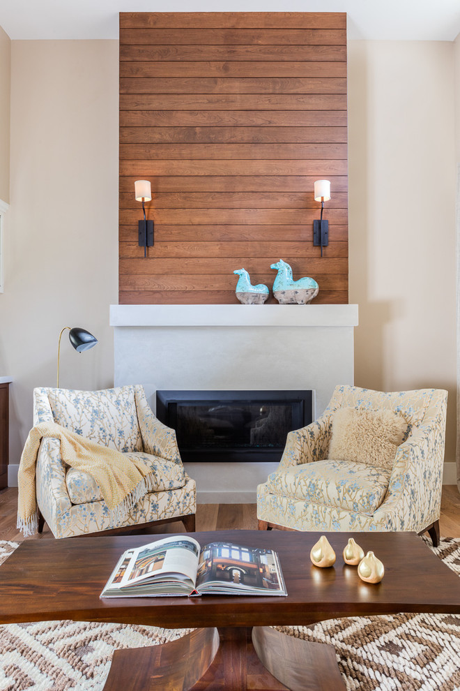 Diseño de salón cerrado de estilo americano de tamaño medio con paredes beige, suelo de madera clara, todas las chimeneas y marco de chimenea de yeso