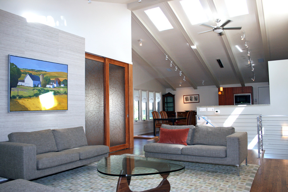 Idée de décoration pour un salon design ouvert avec un mur blanc et un sol en bois brun.