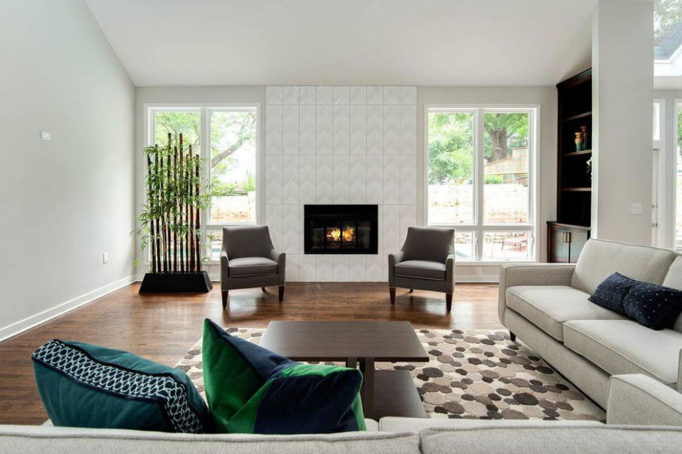 This is an example of a large classic open plan living room in Kansas City with grey walls, medium hardwood flooring, a standard fireplace, a tiled fireplace surround and brown floors.