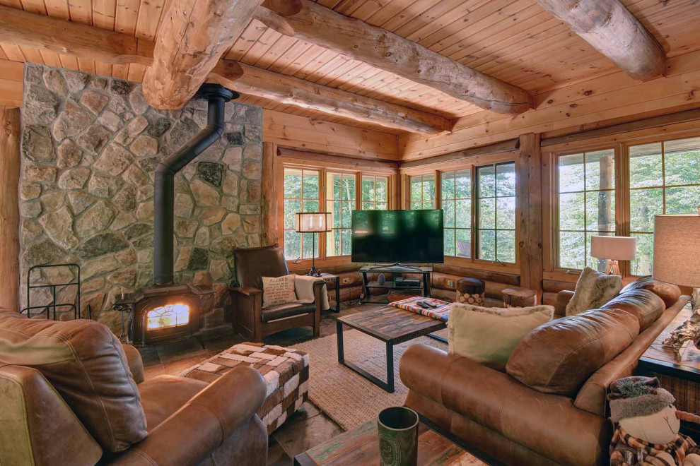 Large mountain style brown floor living room photo with beige walls, a wood stove, a tile fireplace and a tv stand