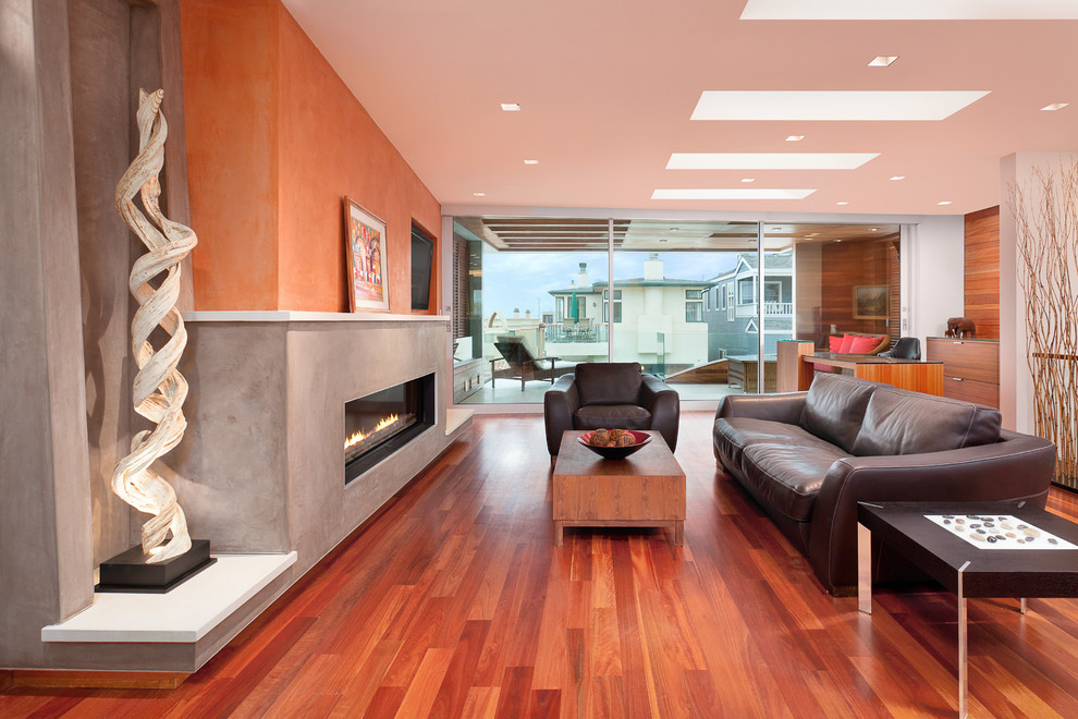 Mittelgroßes, Abgetrenntes Modernes Wohnzimmer mit Gaskamin, bunten Wänden, braunem Holzboden, verputzter Kaminumrandung und rotem Boden in Los Angeles