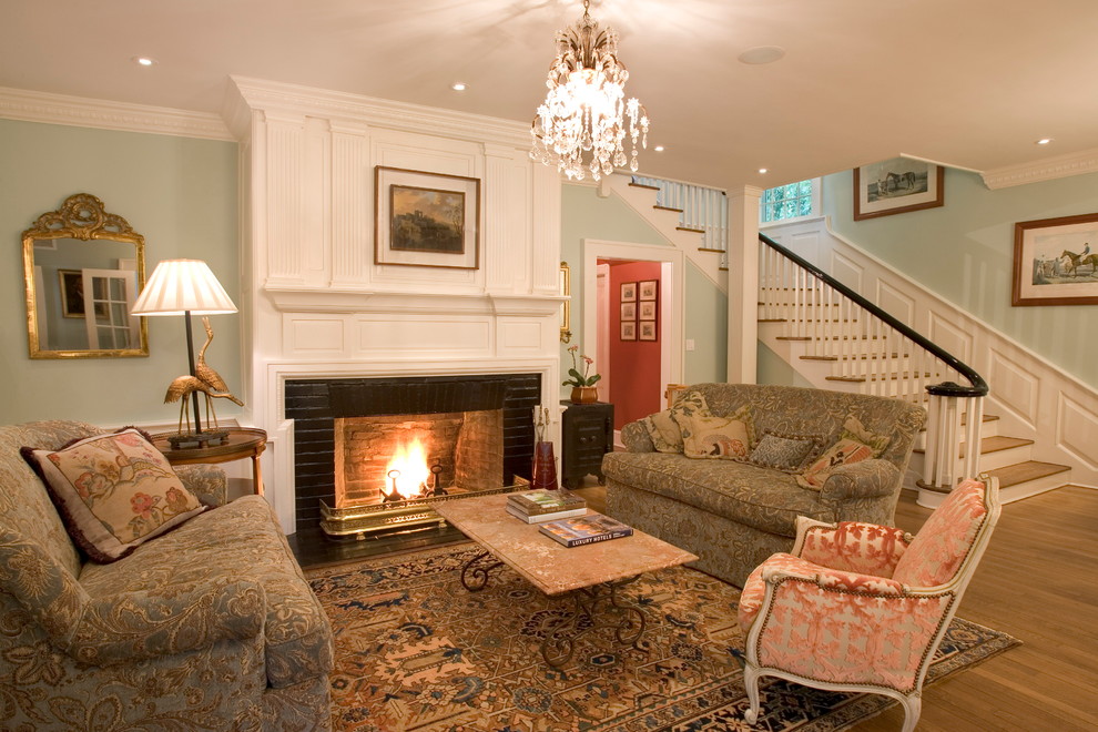 Exemple d'un grand salon chic ouvert avec un mur vert, une cheminée standard, un manteau de cheminée en brique, aucun téléviseur, un sol en bois brun et un sol marron.
