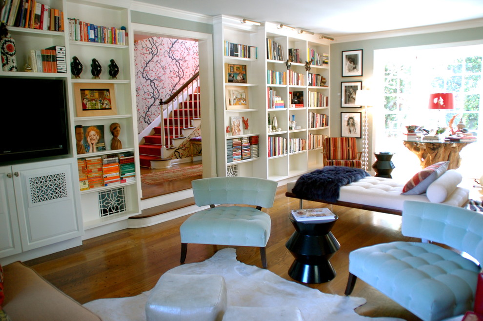 Cette photo montre un salon éclectique avec une bibliothèque ou un coin lecture, un mur bleu, un téléviseur encastré et éclairage.