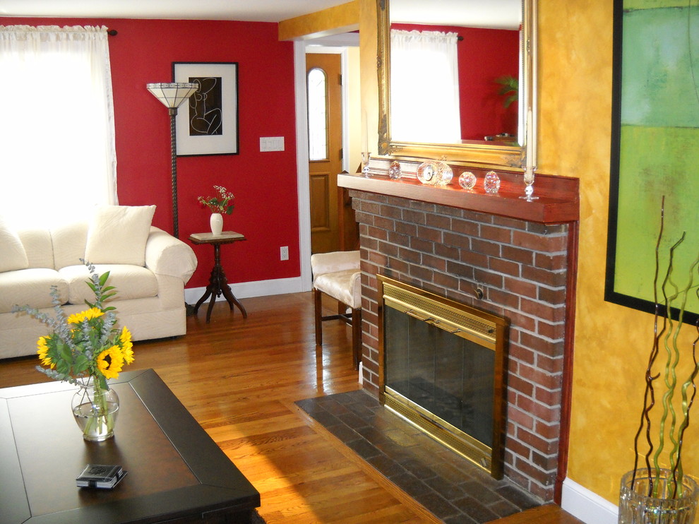 Foto de salón bohemio con paredes rojas, suelo de madera clara, todas las chimeneas y marco de chimenea de ladrillo