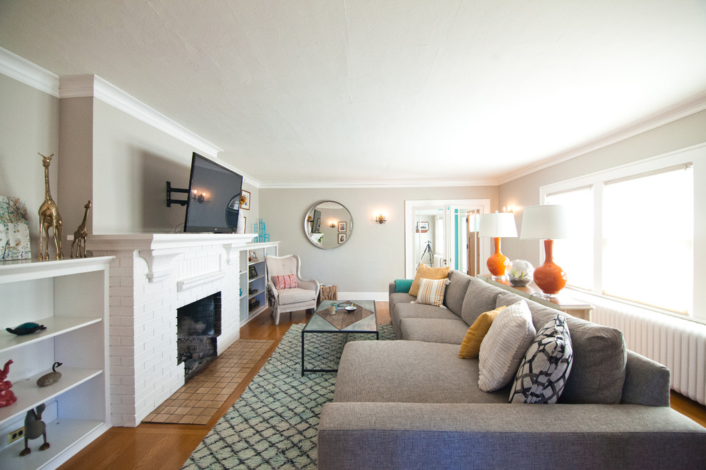 Стильный дизайн: изолированная гостиная комната среднего размера в стиле неоклассика (современная классика) с серыми стенами, паркетным полом среднего тона, стандартным камином, фасадом камина из кирпича и телевизором на стене - последний тренд