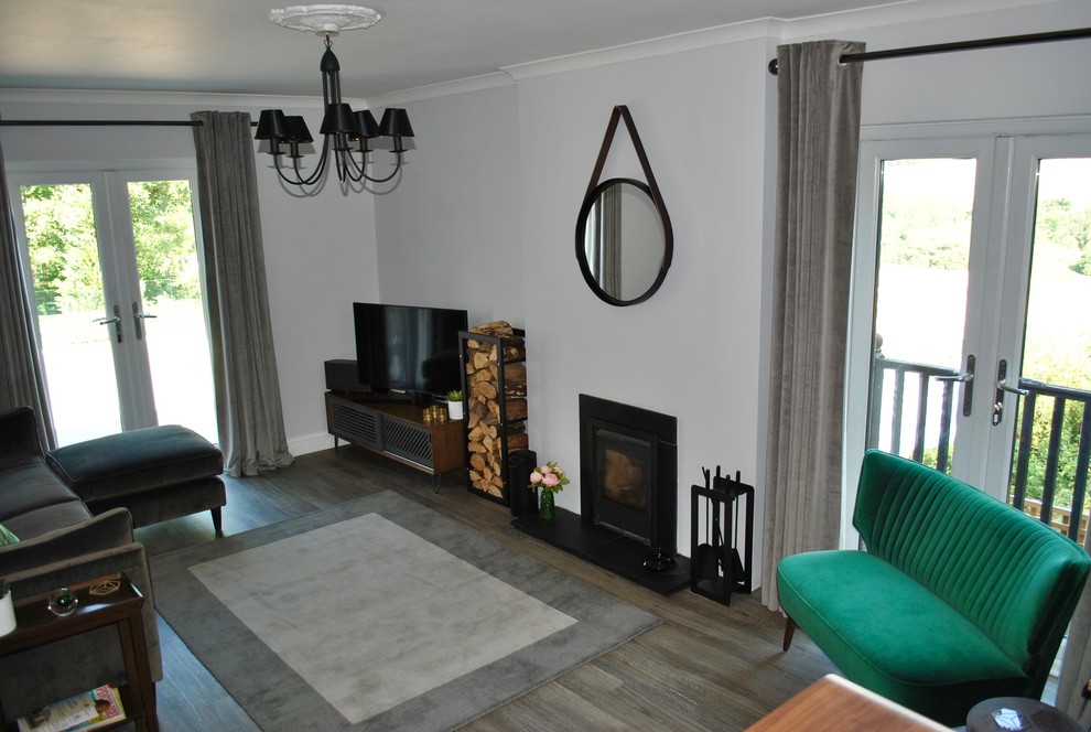 Пример оригинального дизайна: двухуровневая гостиная комната среднего размера в современном стиле с серыми стенами, полом из ламината, печью-буржуйкой, фасадом камина из плитки, отдельно стоящим телевизором и серым полом