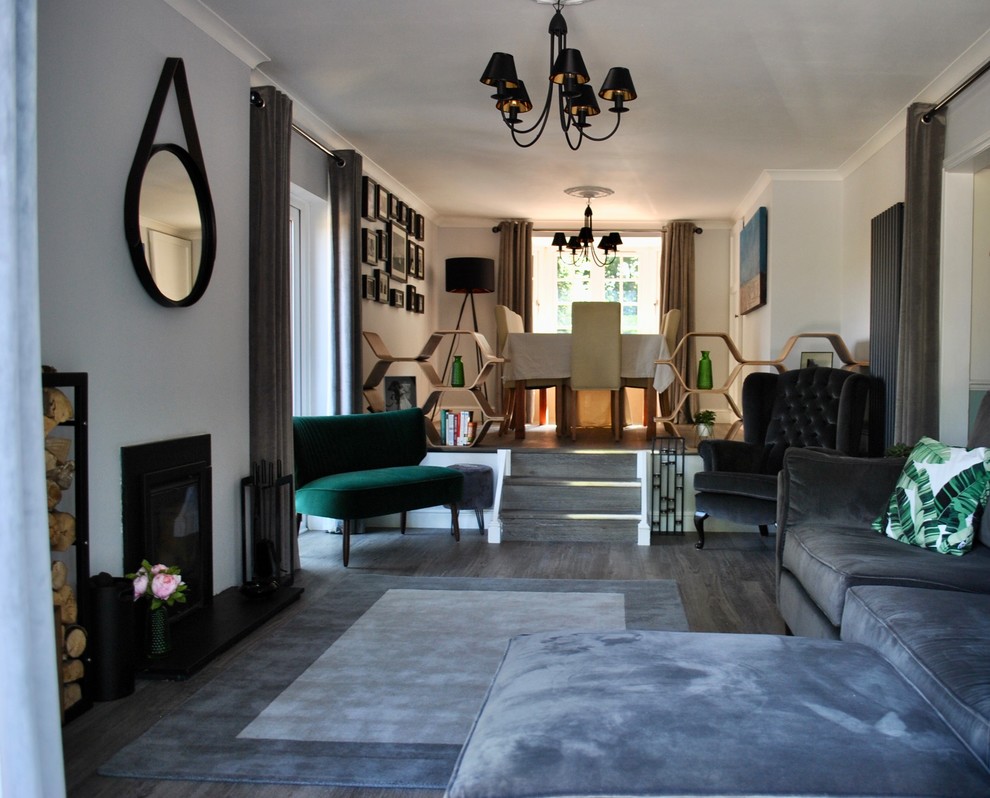 Cette image montre un salon mansardé ou avec mezzanine design de taille moyenne avec un mur gris, sol en stratifié, un poêle à bois, un manteau de cheminée en carrelage, un téléviseur indépendant et un sol gris.