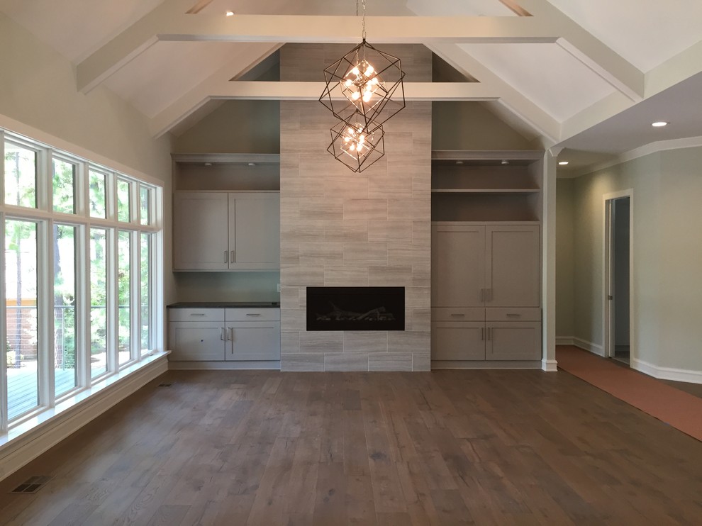 Example of a mid-sized trendy formal and open concept dark wood floor and brown floor living room design in Raleigh with gray walls, a standard fireplace, a tile fireplace and a media wall