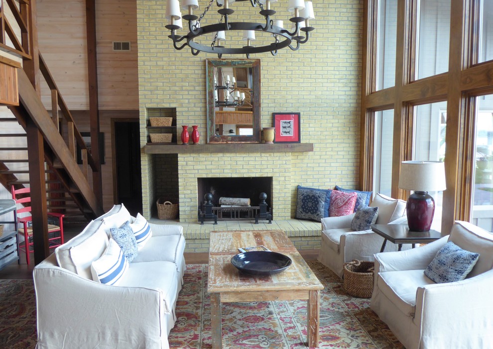 Exemple d'un grand salon montagne ouvert avec un mur beige, un sol en vinyl, une cheminée standard, un manteau de cheminée en brique, aucun téléviseur et un sol marron.