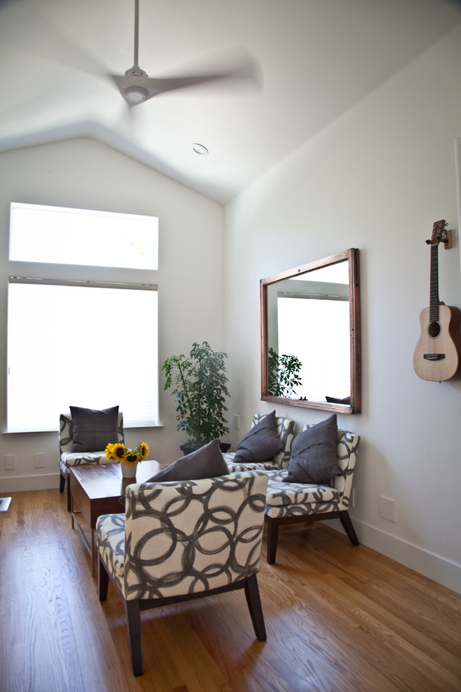 Modelo de salón cerrado actual de tamaño medio sin chimenea con paredes blancas, televisor colgado en la pared y suelo de madera en tonos medios