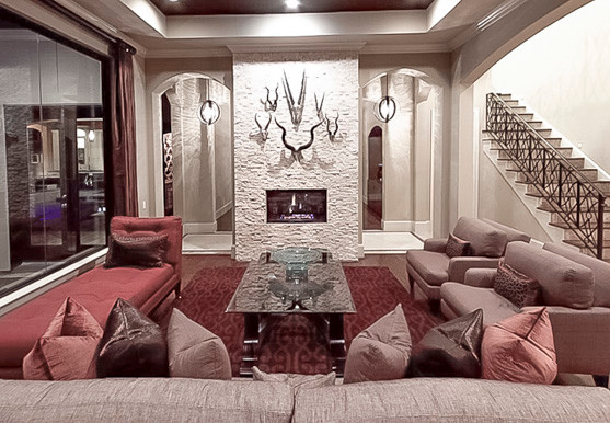 Großes, Repräsentatives, Fernseherloses, Offenes Mediterranes Wohnzimmer mit beiger Wandfarbe, braunem Holzboden, Tunnelkamin und Kaminumrandung aus Stein in Houston