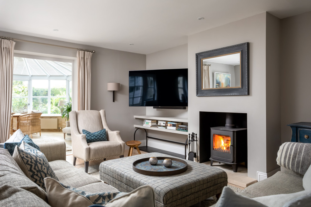 Photo of a large nautical formal enclosed living room in Gloucestershire with grey walls, a wood burning stove, a wall mounted tv, beige floors, light hardwood flooring and a metal fireplace surround.
