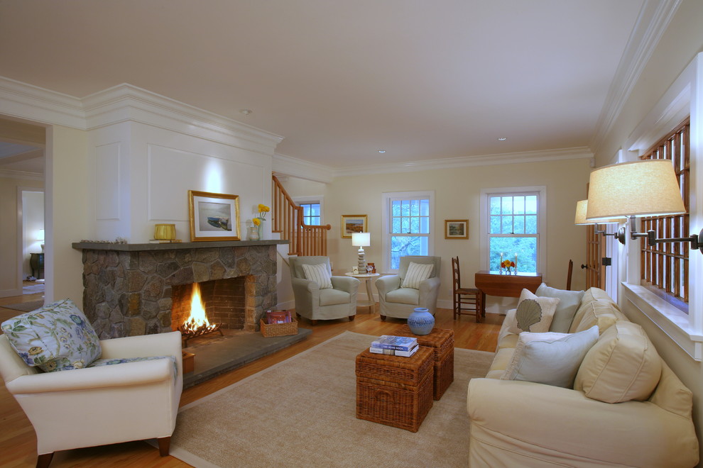 Inspiration pour un grand salon traditionnel ouvert avec un manteau de cheminée en pierre, un mur beige, un sol en bois brun et une cheminée standard.