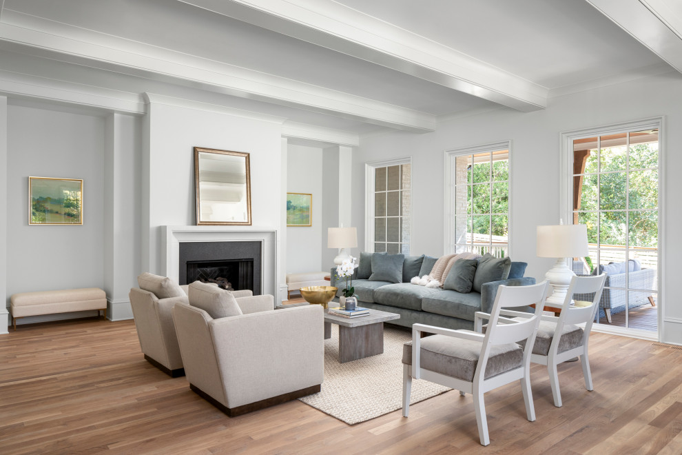 Großes, Offenes Maritimes Wohnzimmer mit beiger Wandfarbe, braunem Holzboden, Kamin, Kaminumrandung aus Beton und braunem Boden in Charlotte