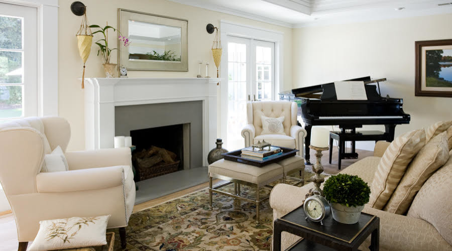 This is an example of a medium sized classic enclosed living room in New York with yellow walls, light hardwood flooring, a standard fireplace, a plastered fireplace surround and no tv.