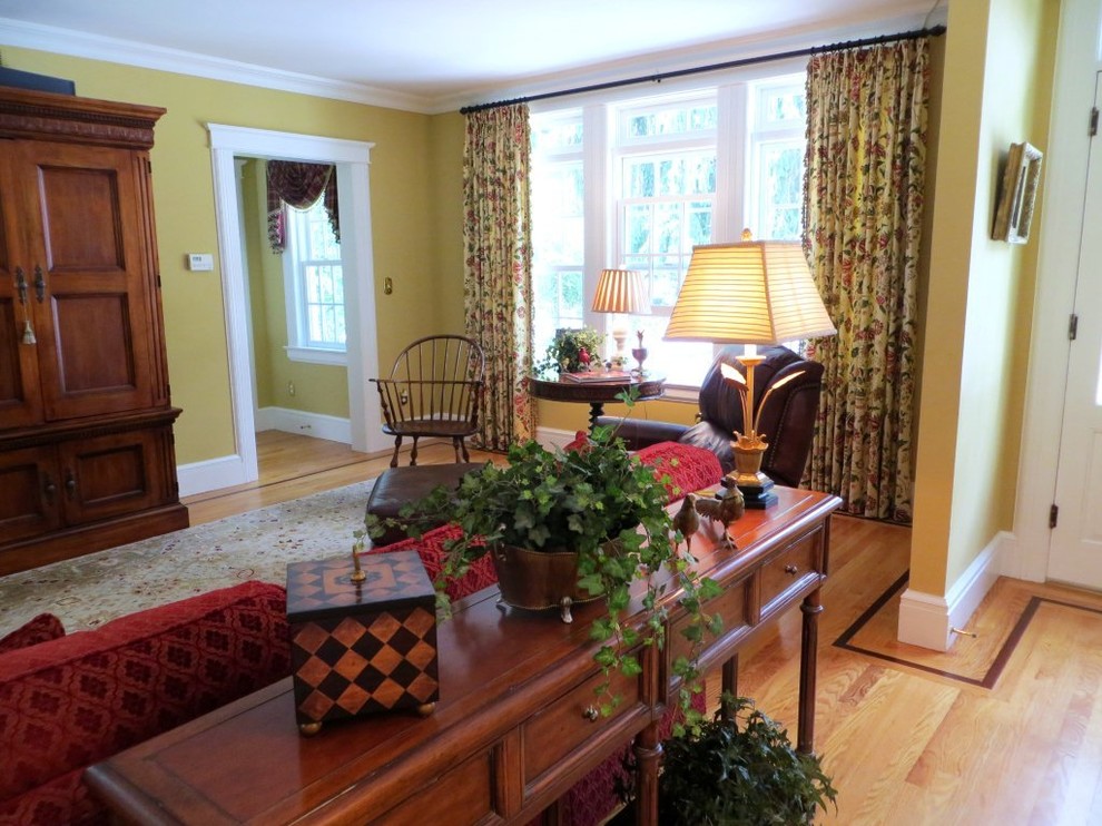 Imagen de salón abierto tradicional de tamaño medio sin chimenea con paredes amarillas, suelo de madera en tonos medios y televisor retractable