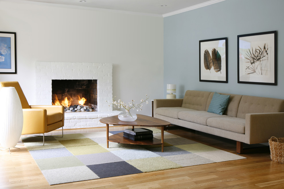 Cette image montre un petit salon minimaliste ouvert avec un mur multicolore, parquet clair, une cheminée standard et un manteau de cheminée en brique.