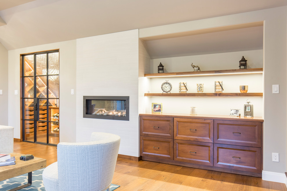 Cette photo montre un salon de taille moyenne et ouvert avec un bar de salon, un mur gris, un sol en bois brun, une cheminée standard, un manteau de cheminée en carrelage et un sol marron.