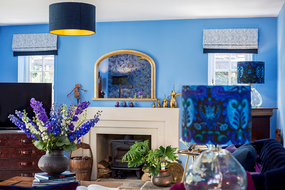 На фото: большая гостиная комната в стиле фьюжн с синими стенами, ковровым покрытием, печью-буржуйкой, фасадом камина из камня и обоями на стенах