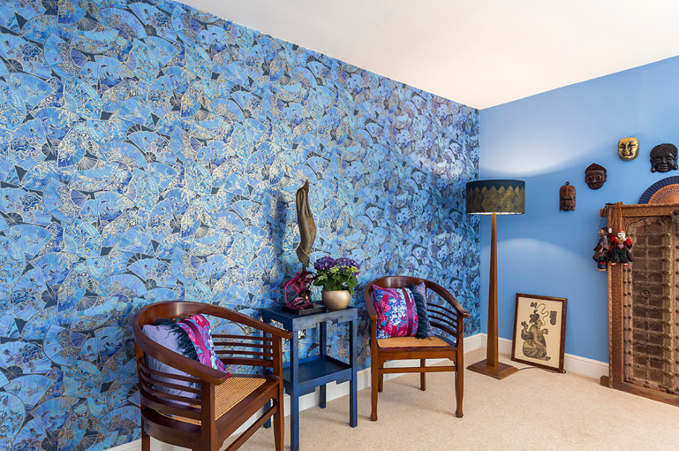 Inspiration pour un grand salon bohème avec un mur bleu, moquette, un poêle à bois, un manteau de cheminée en pierre et du papier peint.