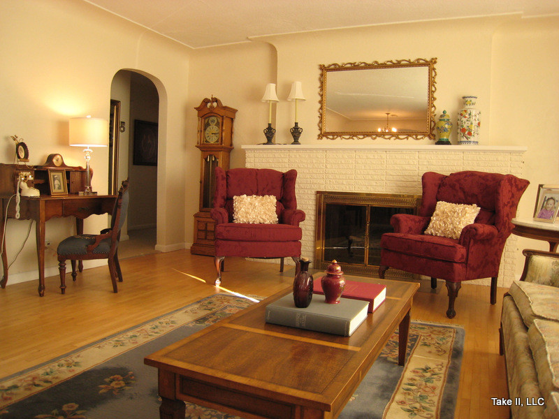 Kleines, Abgetrenntes Klassisches Wohnzimmer mit beiger Wandfarbe, braunem Holzboden, Kamin und Kaminumrandung aus Backstein in Sonstige