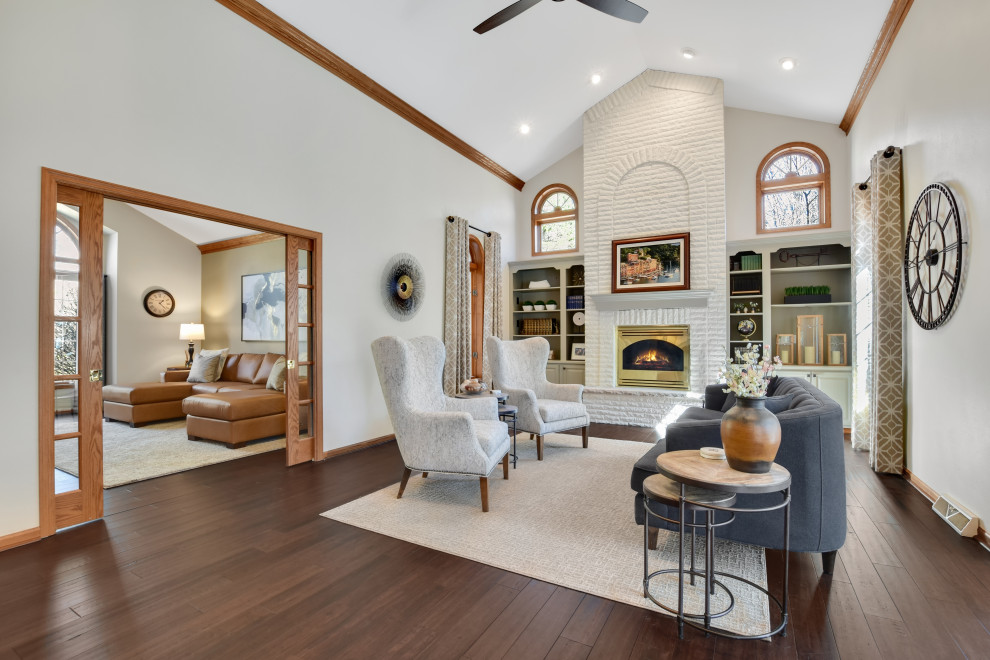 Inspiration for a large transitional formal and open concept medium tone wood floor and brown floor living room remodel in Other with gray walls, a wood stove and a brick fireplace