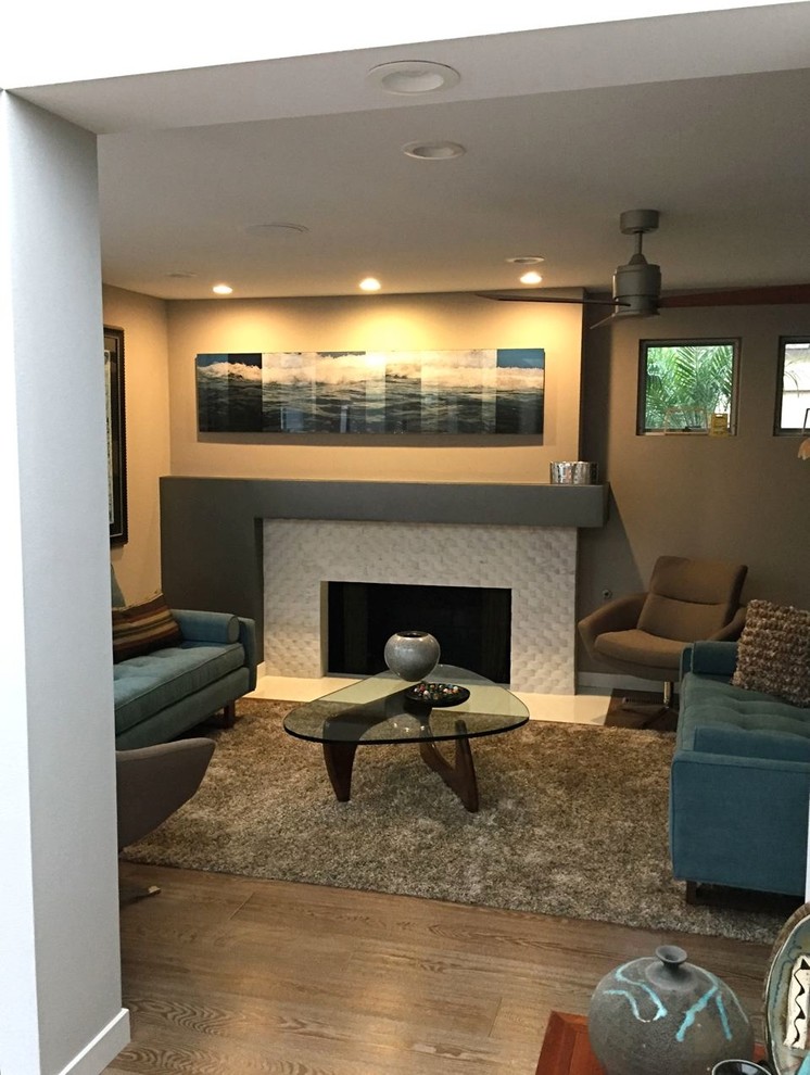Example of a small trendy formal and open concept medium tone wood floor living room design in Los Angeles with no tv, a standard fireplace, a stone fireplace and gray walls