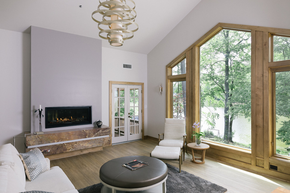 Свежая идея для дизайна: большая изолированная гостиная комната в стиле модернизм с белыми стенами, светлым паркетным полом, горизонтальным камином, фасадом камина из камня и коричневым полом без телевизора - отличное фото интерьера