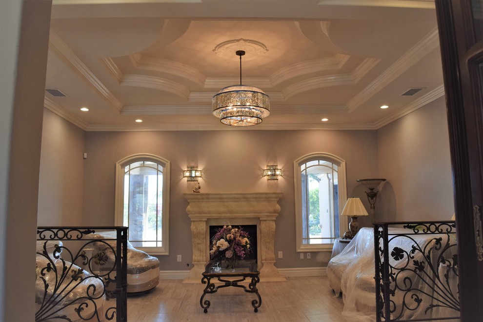 This is an example of a large mediterranean formal open plan living room with brown walls, light hardwood flooring, a standard fireplace, a stone fireplace surround, no tv and beige floors.