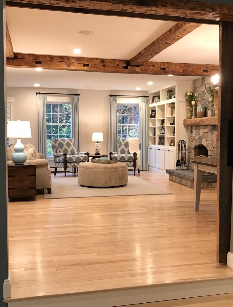 Photo of a medium sized farmhouse formal living room in Portland Maine with grey walls, light hardwood flooring, a standard fireplace, a stone fireplace surround, no tv and exposed beams.