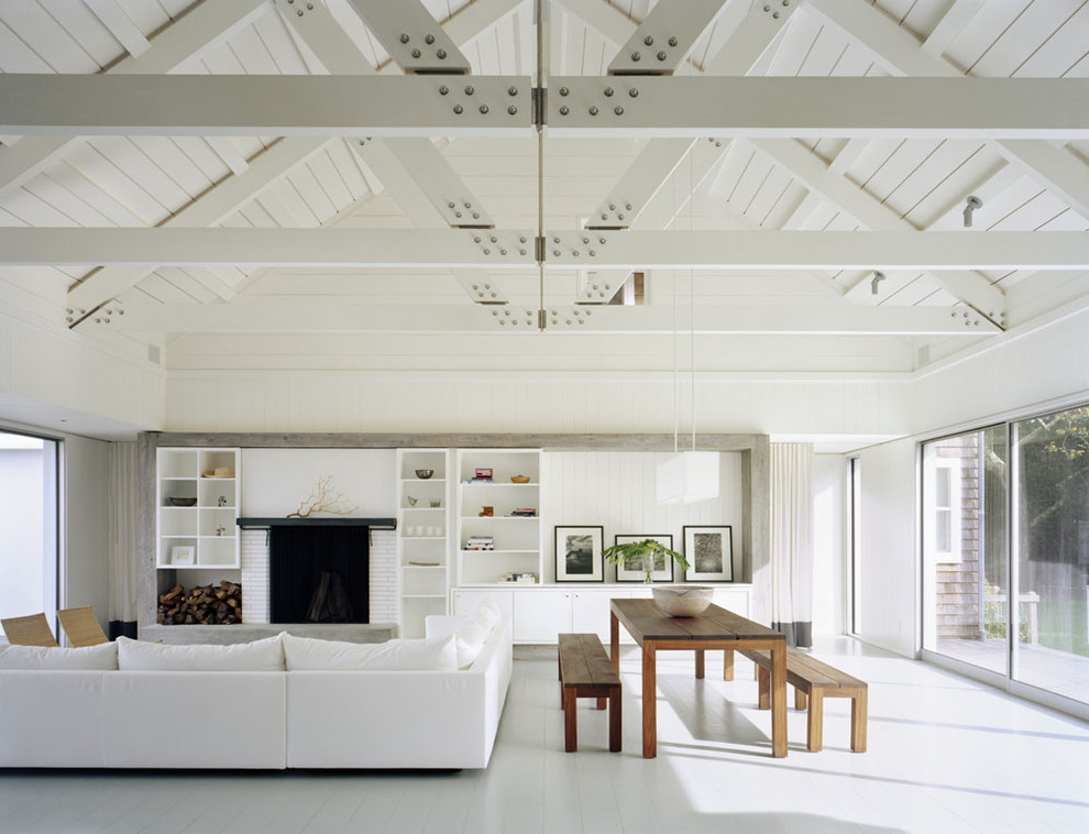 Huge trendy white floor living room photo in New York with white walls and a brick fireplace
