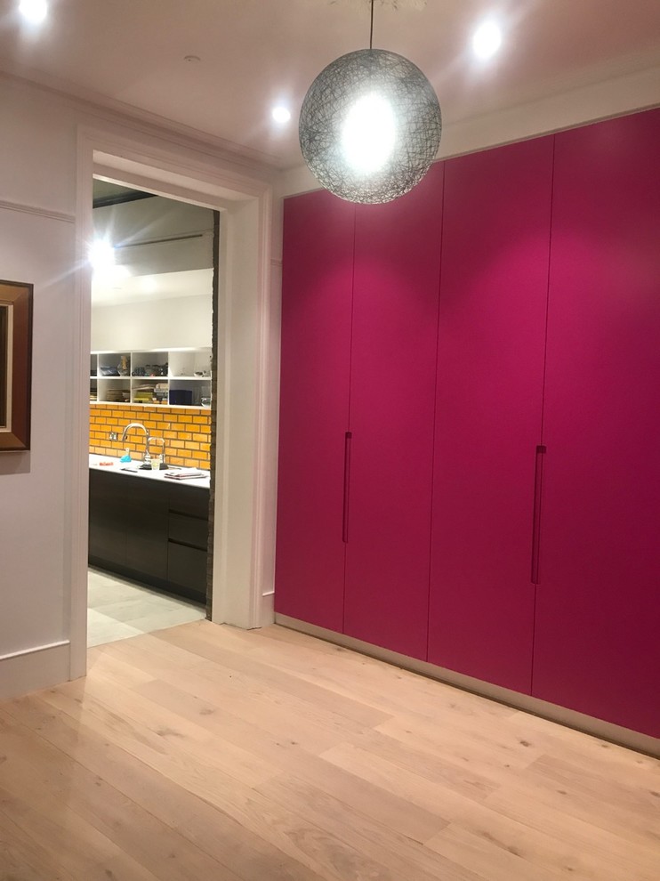 Mittelgroßes, Abgetrenntes Modernes Wohnzimmer mit rosa Wandfarbe, hellem Holzboden, verstecktem TV und beigem Boden in London