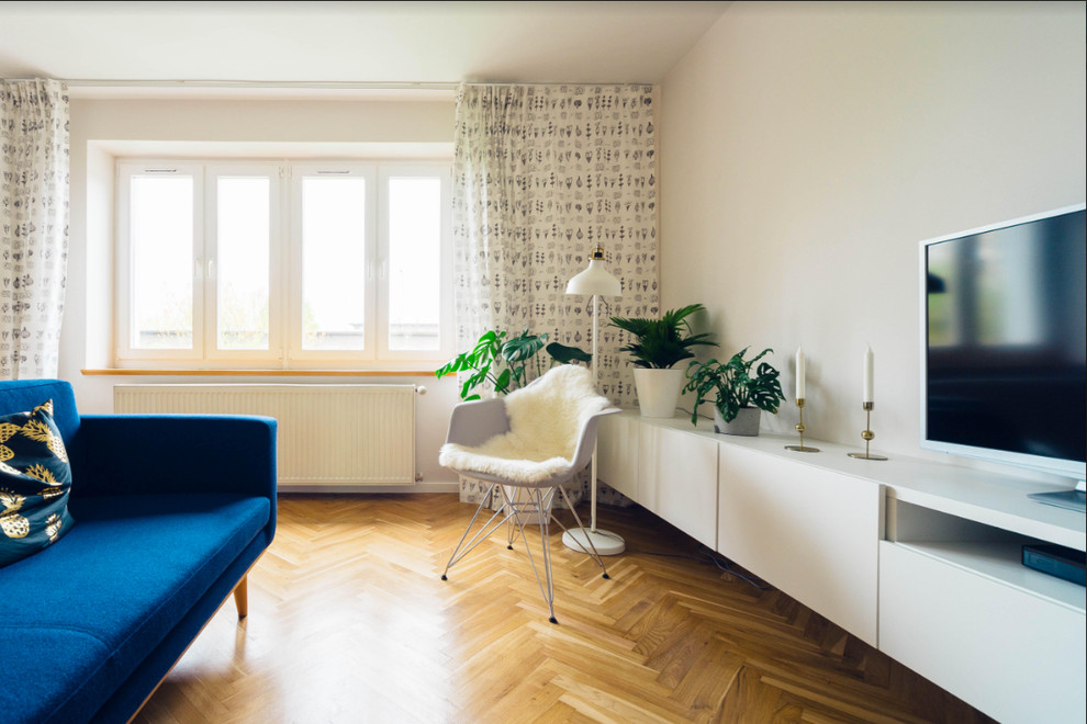 Modelo de salón abierto actual de tamaño medio sin chimenea con paredes blancas, suelo de madera en tonos medios, suelo marrón y televisor independiente