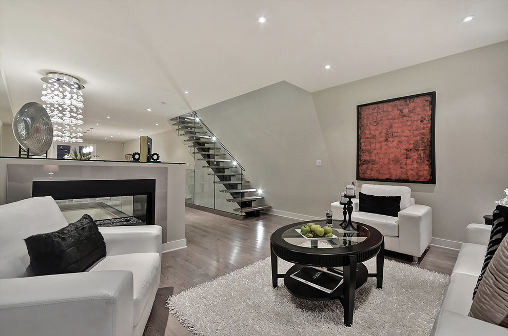 Photo of a medium sized contemporary formal mezzanine living room in Ottawa with beige walls, laminate floors, a two-sided fireplace, a metal fireplace surround, no tv and brown floors.