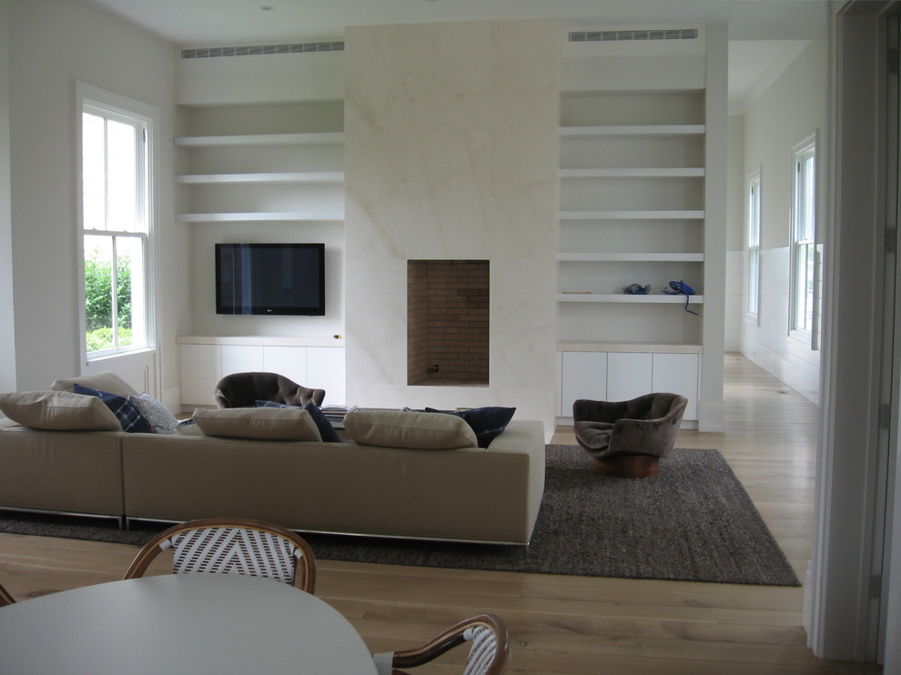 Пример оригинального дизайна: большая изолированная гостиная комната в стиле неоклассика (современная классика) с бежевыми стенами, паркетным полом среднего тона, стандартным камином, фасадом камина из камня и телевизором на стене