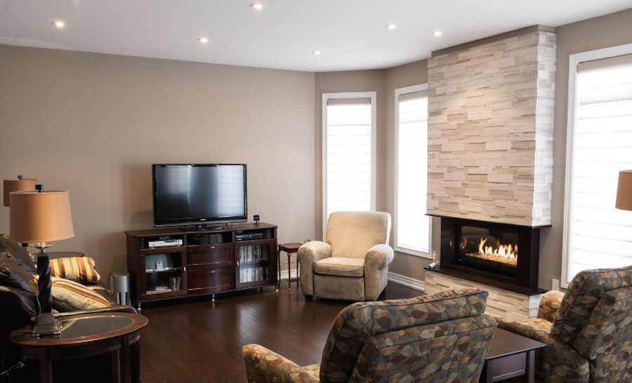 Mittelgroßes, Abgetrenntes Klassisches Wohnzimmer mit brauner Wandfarbe, dunklem Holzboden, Kamin, Kaminumrandung aus Stein und freistehendem TV in Toronto
