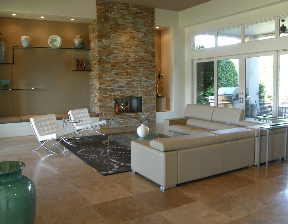 Imagen de salón abierto minimalista con paredes beige, marco de chimenea de piedra y suelo de travertino