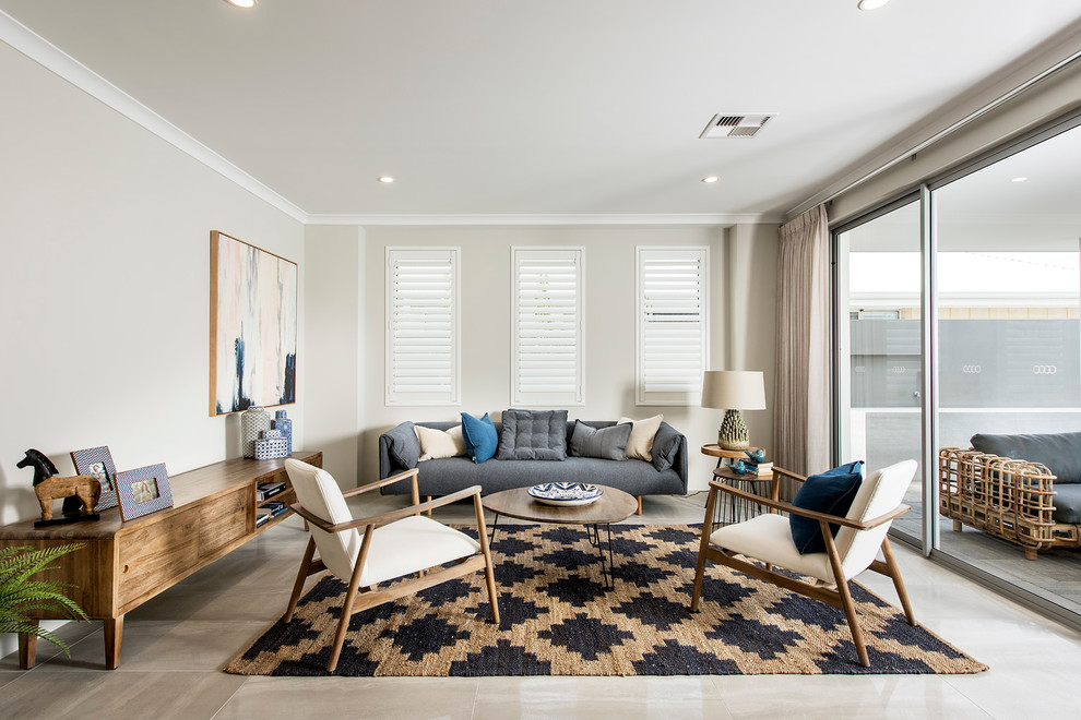 На фото: открытая гостиная комната в морском стиле с серыми стенами и синим диваном с
