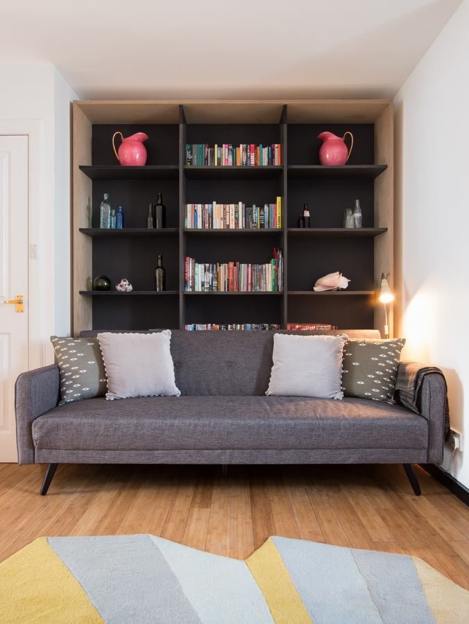 Idee per un piccolo soggiorno eclettico aperto con libreria, pareti beige, pavimento in bambù, stufa a legna, cornice del camino in legno, TV autoportante e pavimento marrone